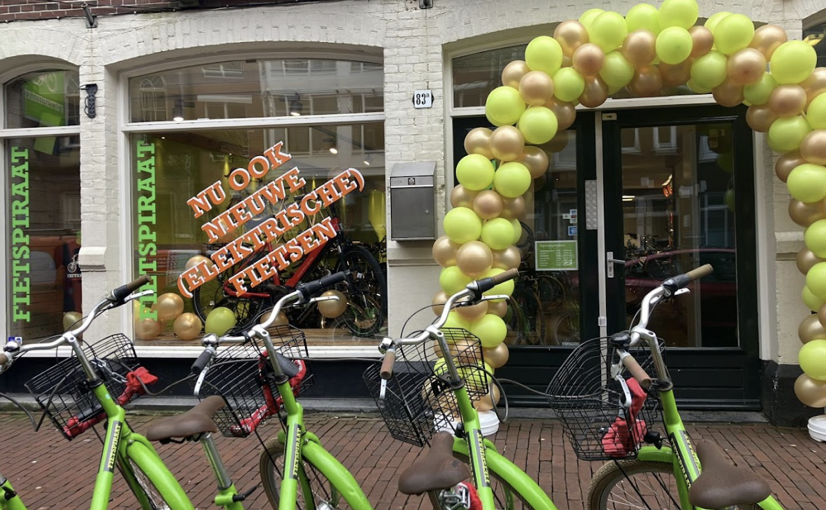 Fietspiraat winkel in Amsterdam met groene huurfietsen voor de deur